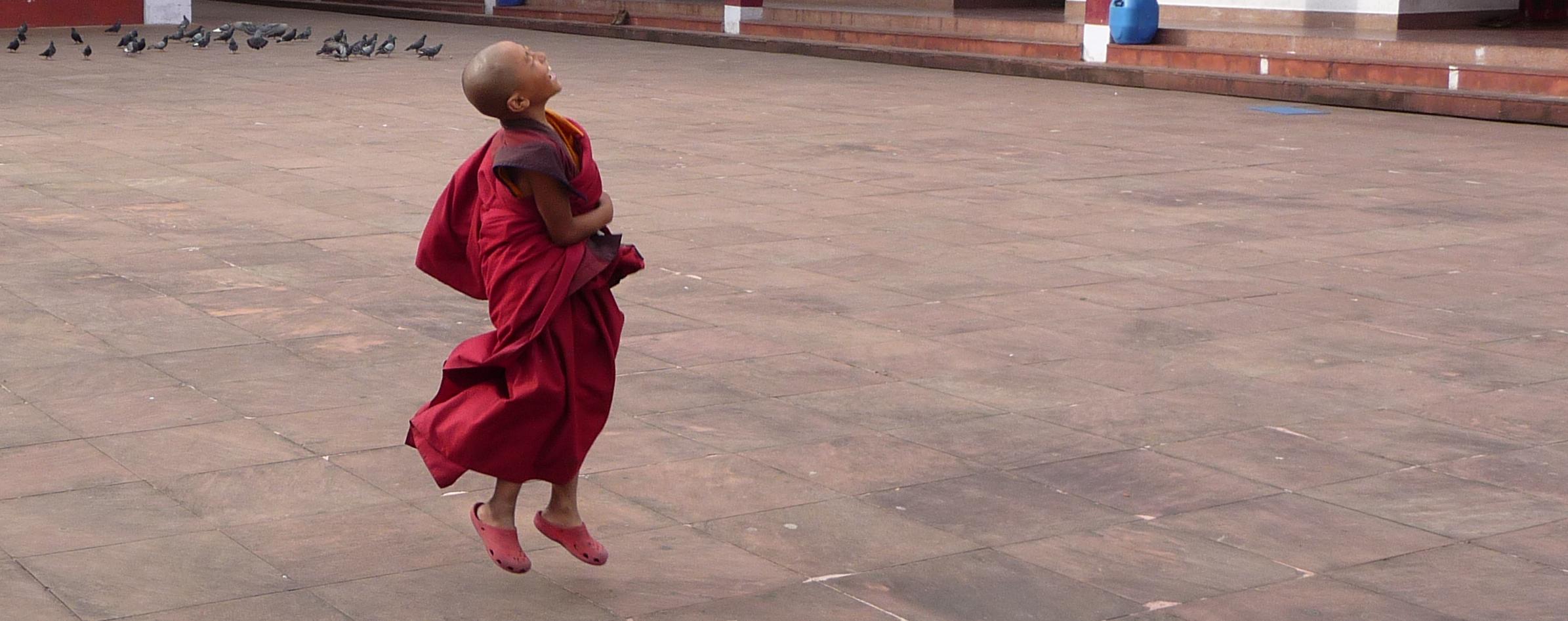 This young monk was playing with a super ball in front of the monastery